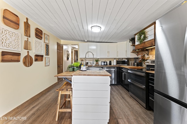 kitchen featuring dark wood finished floors, open shelves, stainless steel appliances, white cabinets, and a sink