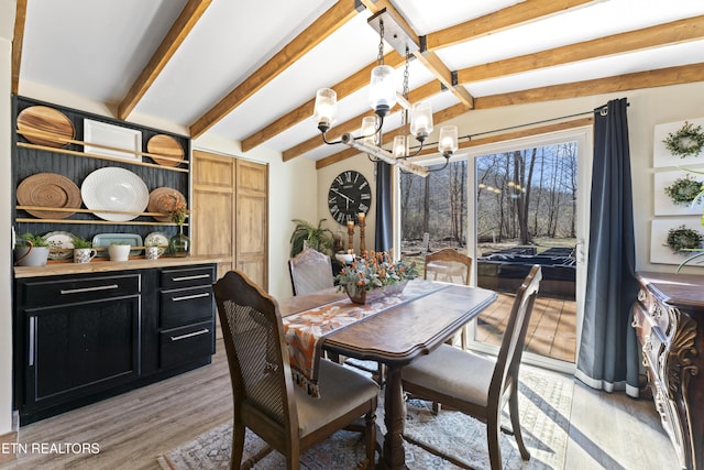 dining room with a chandelier, light wood-type flooring, and vaulted ceiling with beams