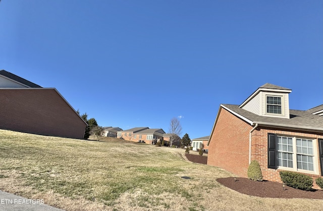 view of side of home with a lawn and brick siding