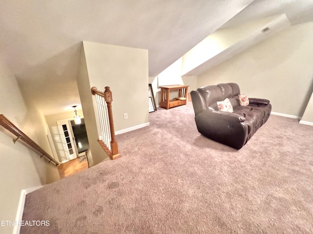 living area with carpet, baseboards, visible vents, and an upstairs landing