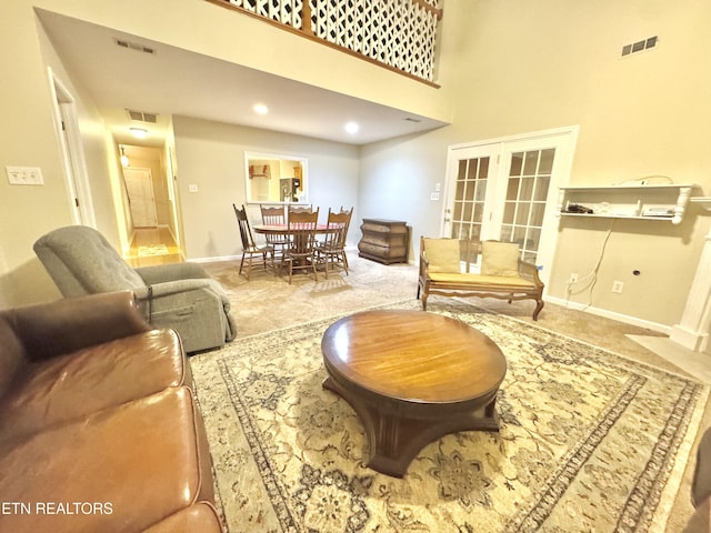 living area featuring carpet, visible vents, baseboards, and french doors