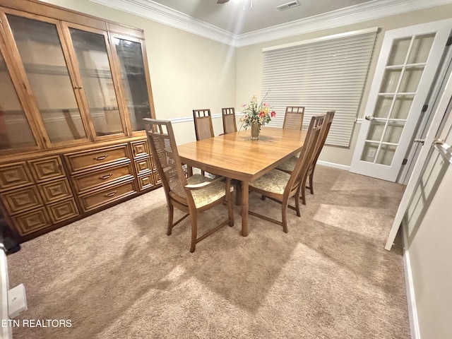 dining space featuring crown molding, ceiling fan, visible vents, and light colored carpet