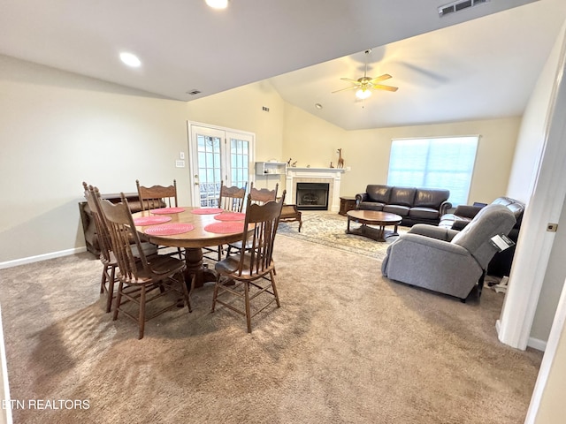 carpeted dining area with vaulted ceiling, a fireplace, baseboards, and plenty of natural light