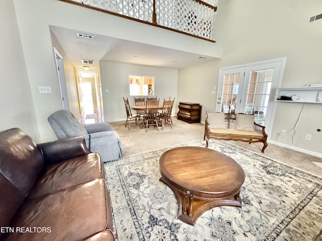 carpeted living area featuring baseboards, a high ceiling, and visible vents