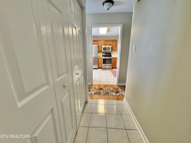 hall featuring light tile patterned floors and baseboards