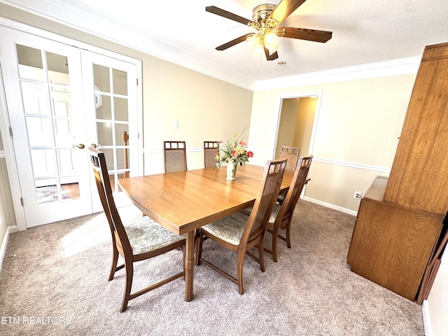 carpeted dining area featuring baseboards, french doors, a ceiling fan, and crown molding