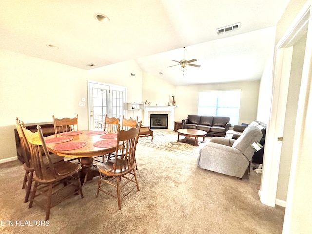 dining space with carpet floors, a fireplace, visible vents, and lofted ceiling