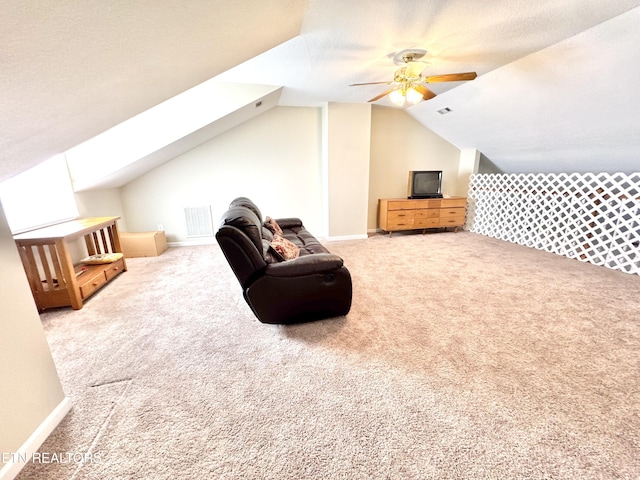 sitting room featuring ceiling fan, vaulted ceiling with skylight, a textured ceiling, carpet flooring, and visible vents