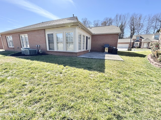 back of property featuring a yard, a patio, brick siding, and central AC unit