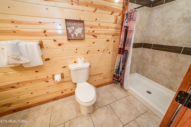 bathroom with toilet, a stall shower, tile patterned flooring, and wood walls