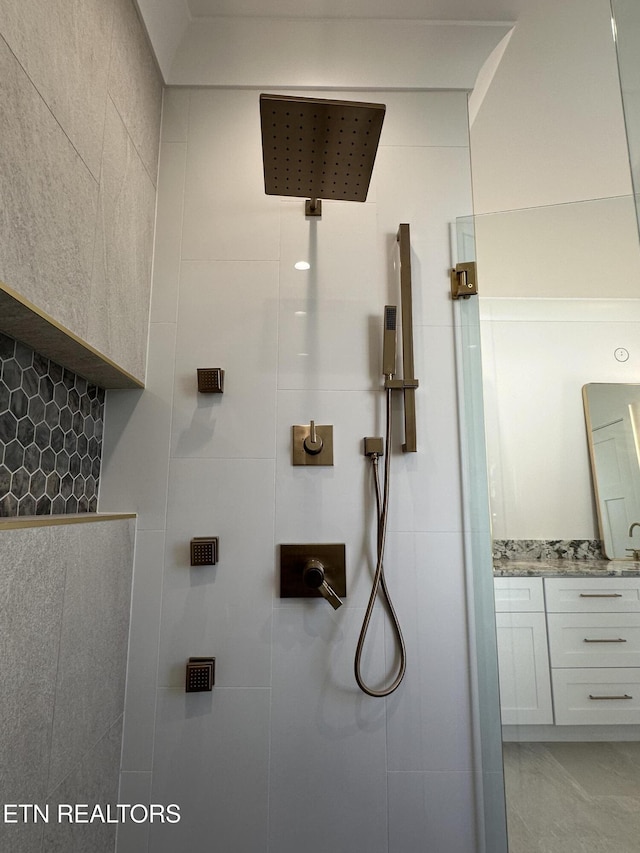 full bath featuring tiled shower and vanity