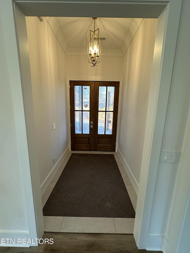 doorway with a notable chandelier, french doors, baseboards, and ornamental molding