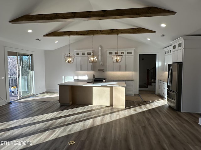 kitchen with an island with sink, backsplash, wood finished floors, and freestanding refrigerator