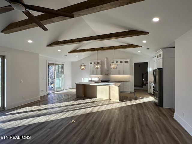 kitchen featuring an island with sink, glass insert cabinets, freestanding refrigerator, light countertops, and a sink