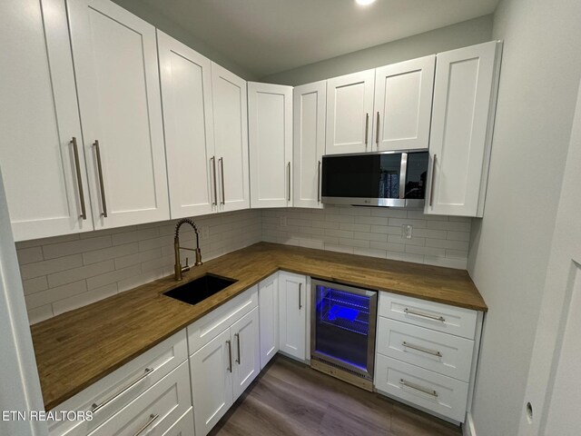 kitchen with wine cooler, a sink, wood counters, tasteful backsplash, and stainless steel microwave