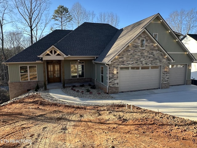 view of front of house featuring french doors, roof with shingles, an attached garage, and concrete driveway