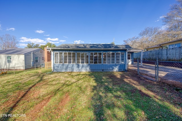 rear view of property with a gate, fence, and a yard