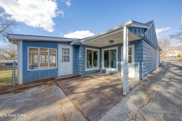 exterior space featuring board and batten siding, a patio area, and fence