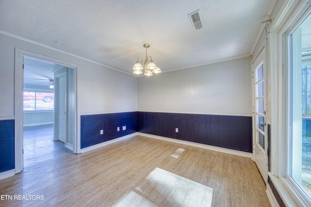 empty room with a notable chandelier, ornamental molding, and wood finished floors