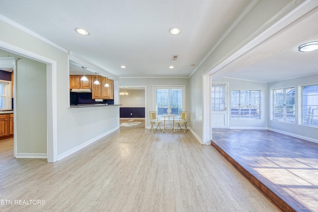 unfurnished living room featuring light wood finished floors, a wealth of natural light, and crown molding