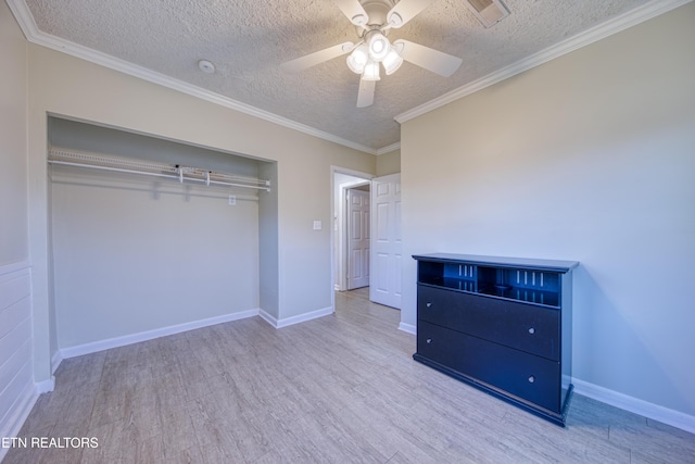 unfurnished bedroom with crown molding, ceiling fan, a textured ceiling, wood finished floors, and baseboards