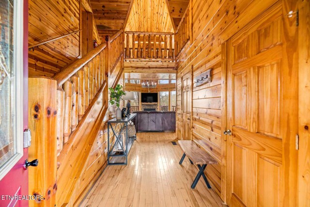 interior space featuring light wood finished floors, stairs, wooden walls, and a high ceiling