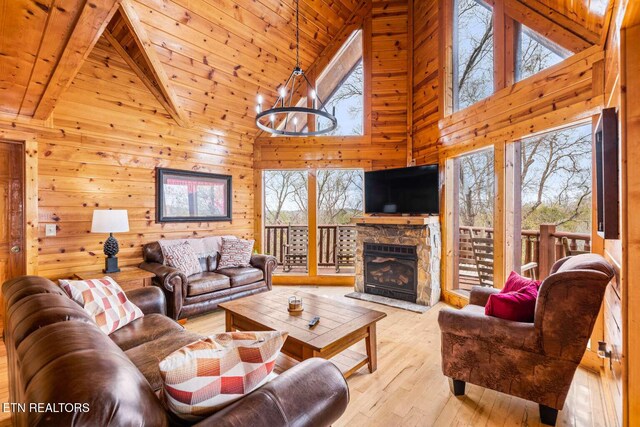 living room with wooden ceiling, light wood-style flooring, wooden walls, a fireplace, and an inviting chandelier