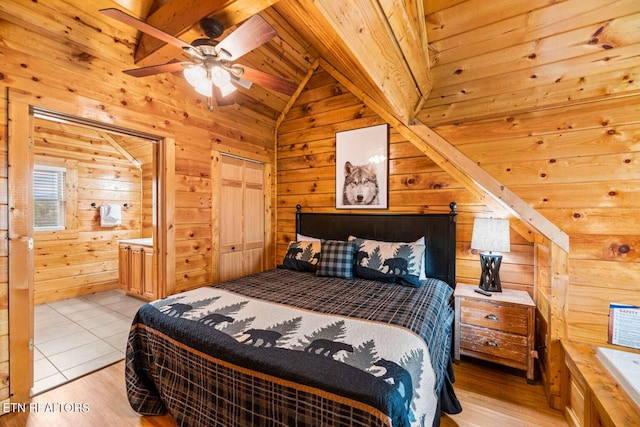 bedroom featuring lofted ceiling, ensuite bathroom, wooden ceiling, wooden walls, and light wood-style floors