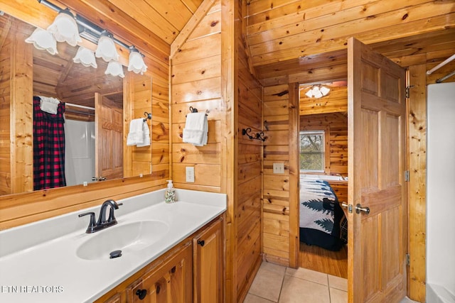 bathroom featuring wooden walls, lofted ceiling, wood ceiling, tile patterned flooring, and vanity