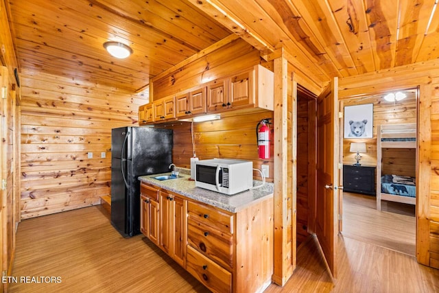 kitchen with wooden ceiling, white microwave, freestanding refrigerator, and wood walls