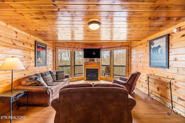 living area featuring wood walls, a fireplace, wood finished floors, and wood ceiling