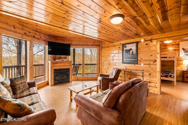 living room featuring wooden walls, wooden ceiling, wood finished floors, vaulted ceiling, and a fireplace