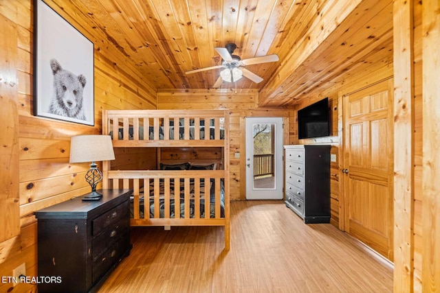 bedroom with access to outside, wood finished floors, wood ceiling, and wooden walls