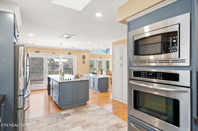 kitchen featuring light wood-style flooring, a kitchen island, appliances with stainless steel finishes, crown molding, and gray cabinetry