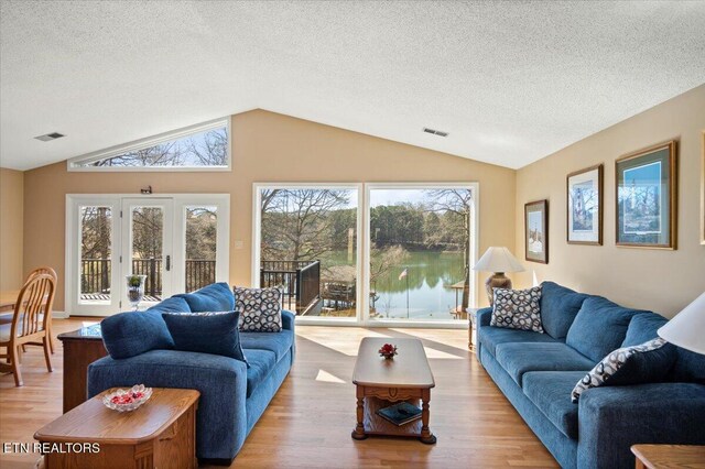 living area featuring a healthy amount of sunlight, visible vents, wood finished floors, and lofted ceiling