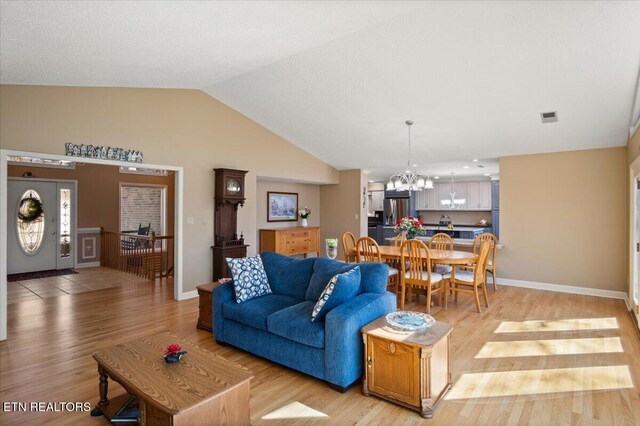 living area featuring visible vents, baseboards, lofted ceiling, light wood-type flooring, and a chandelier