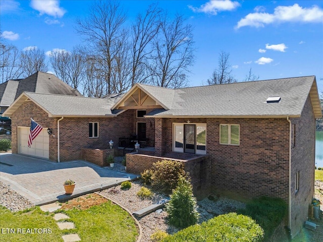 ranch-style home with a garage, decorative driveway, brick siding, and roof with shingles