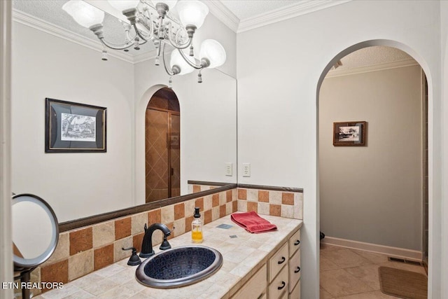 bathroom featuring tile patterned flooring, crown molding, baseboards, backsplash, and an inviting chandelier