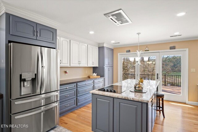 kitchen with visible vents, stainless steel fridge with ice dispenser, a center island, black electric stovetop, and light wood-style floors