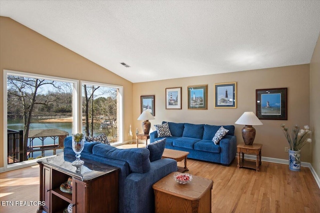 living room with lofted ceiling, visible vents, a textured ceiling, and light wood finished floors