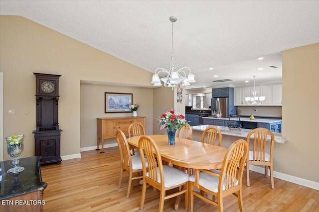 dining area with lofted ceiling, light wood-style flooring, baseboards, and a notable chandelier