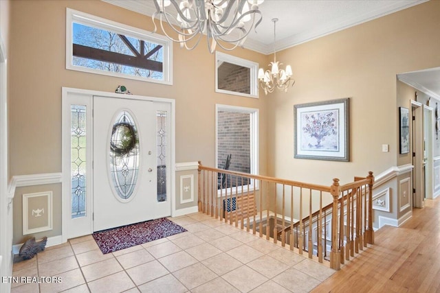 foyer entrance featuring a chandelier, ornamental molding, light tile patterned floors, and a high ceiling