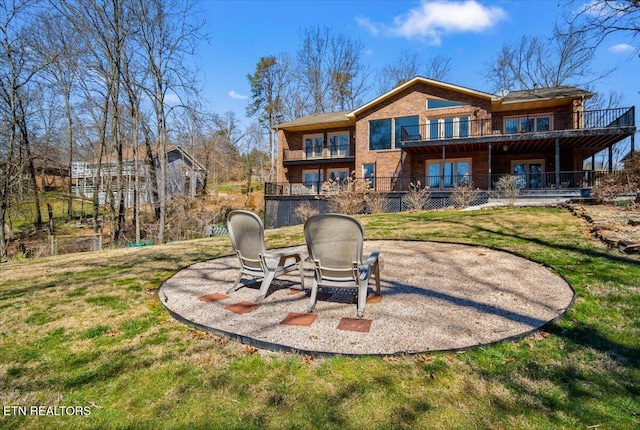 rear view of house with brick siding, a yard, a balcony, and a patio