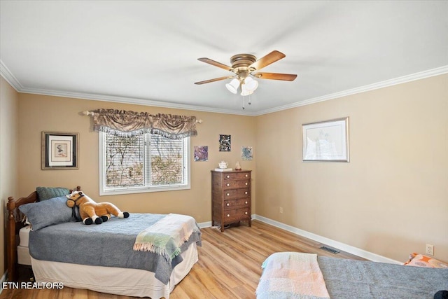 bedroom featuring crown molding, visible vents, light wood-style floors, ceiling fan, and baseboards