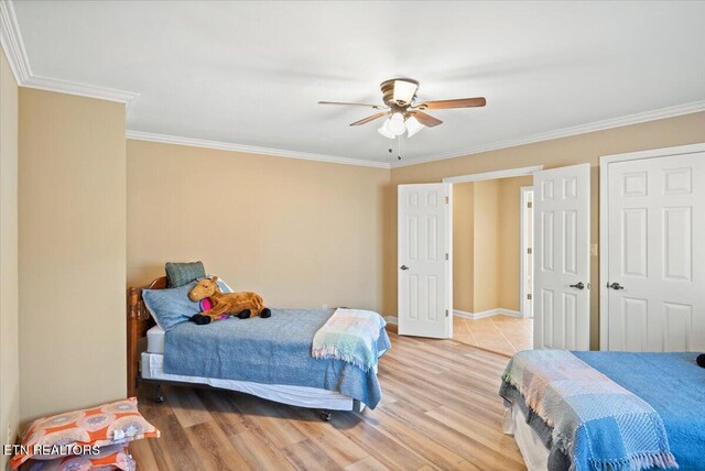 bedroom featuring ornamental molding, light wood-type flooring, baseboards, and a ceiling fan