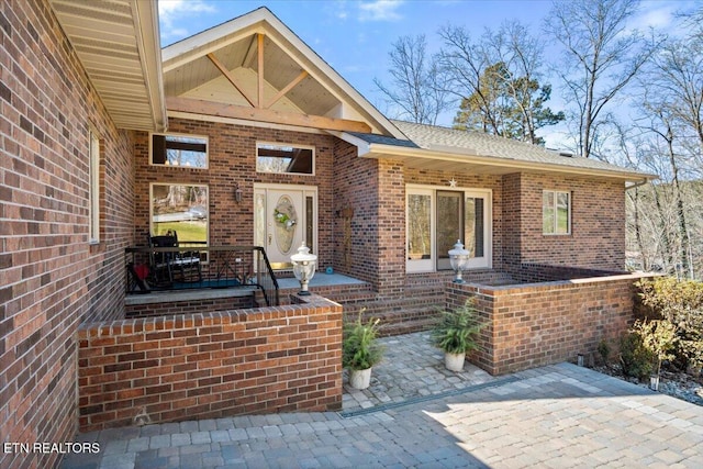 view of exterior entry featuring brick siding