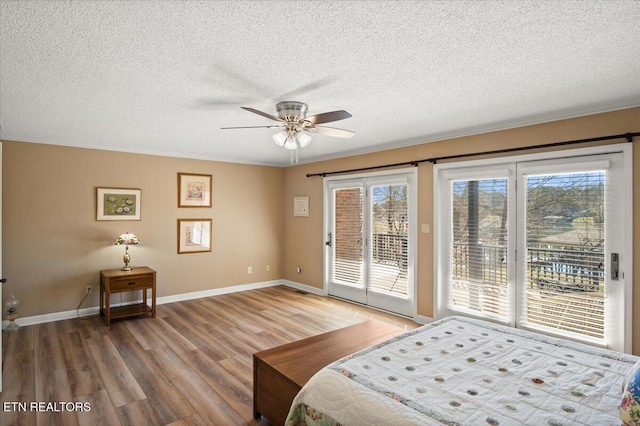 bedroom with access to outside, multiple windows, wood finished floors, and baseboards