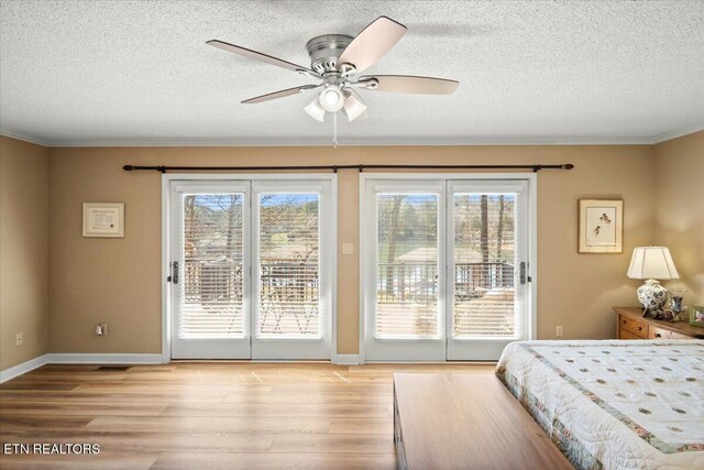 bedroom with light wood finished floors, access to outside, baseboards, and a textured ceiling