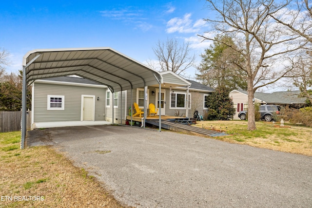 view of front of property with aphalt driveway, a front lawn, fence, and a detached carport