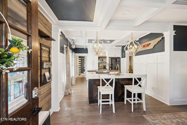 dining area with beam ceiling, coffered ceiling, a notable chandelier, and a decorative wall